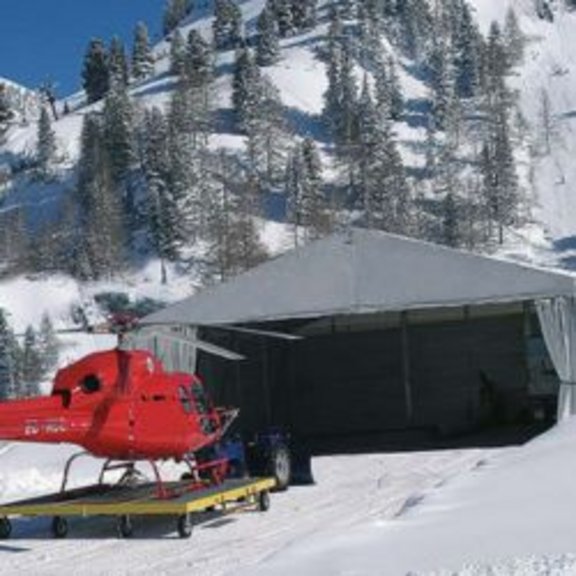 Roter Helikopter mit Hangarzelt im Schnee 